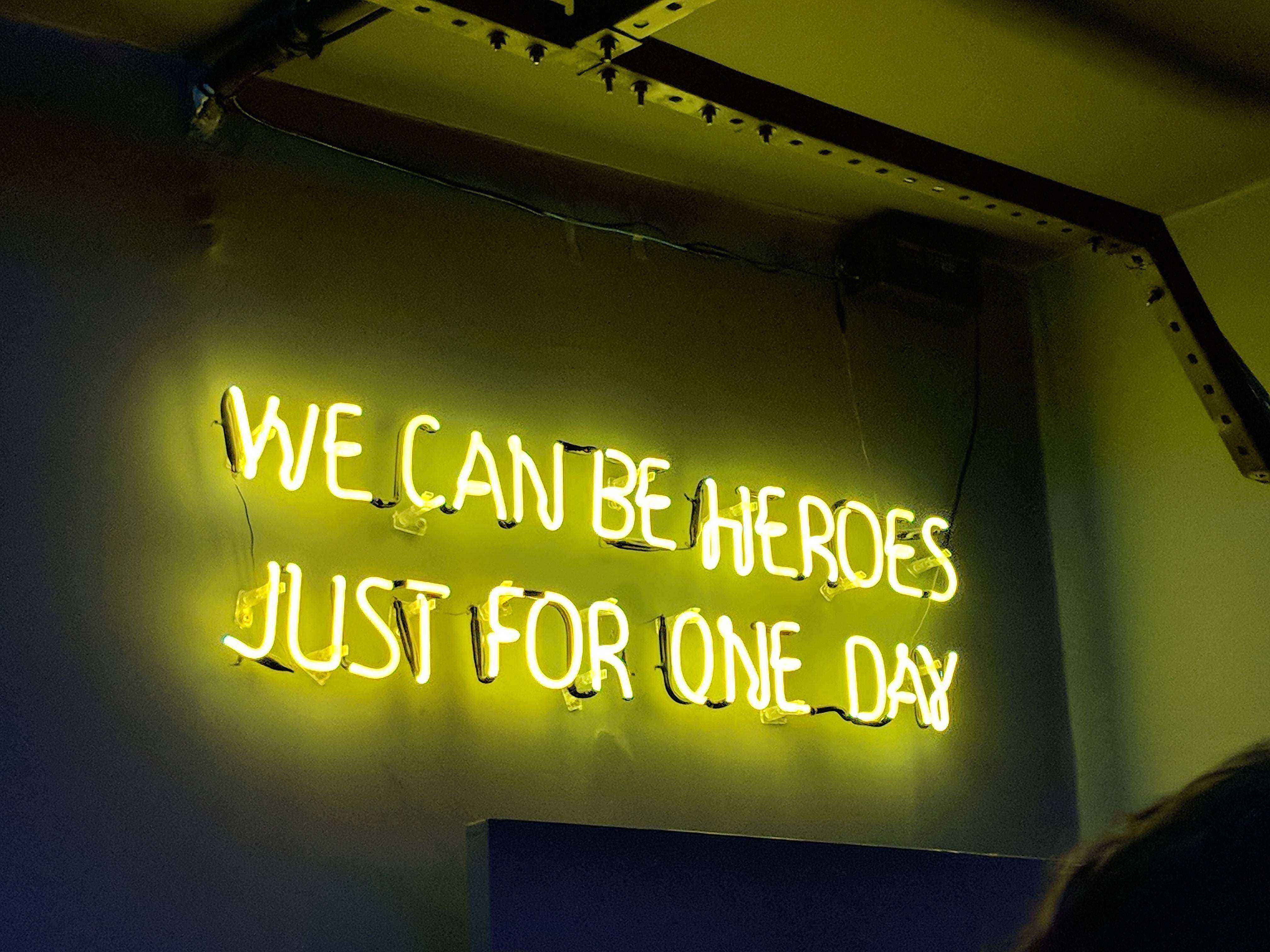 A neon sign saying "We can be heroes just for one day"
